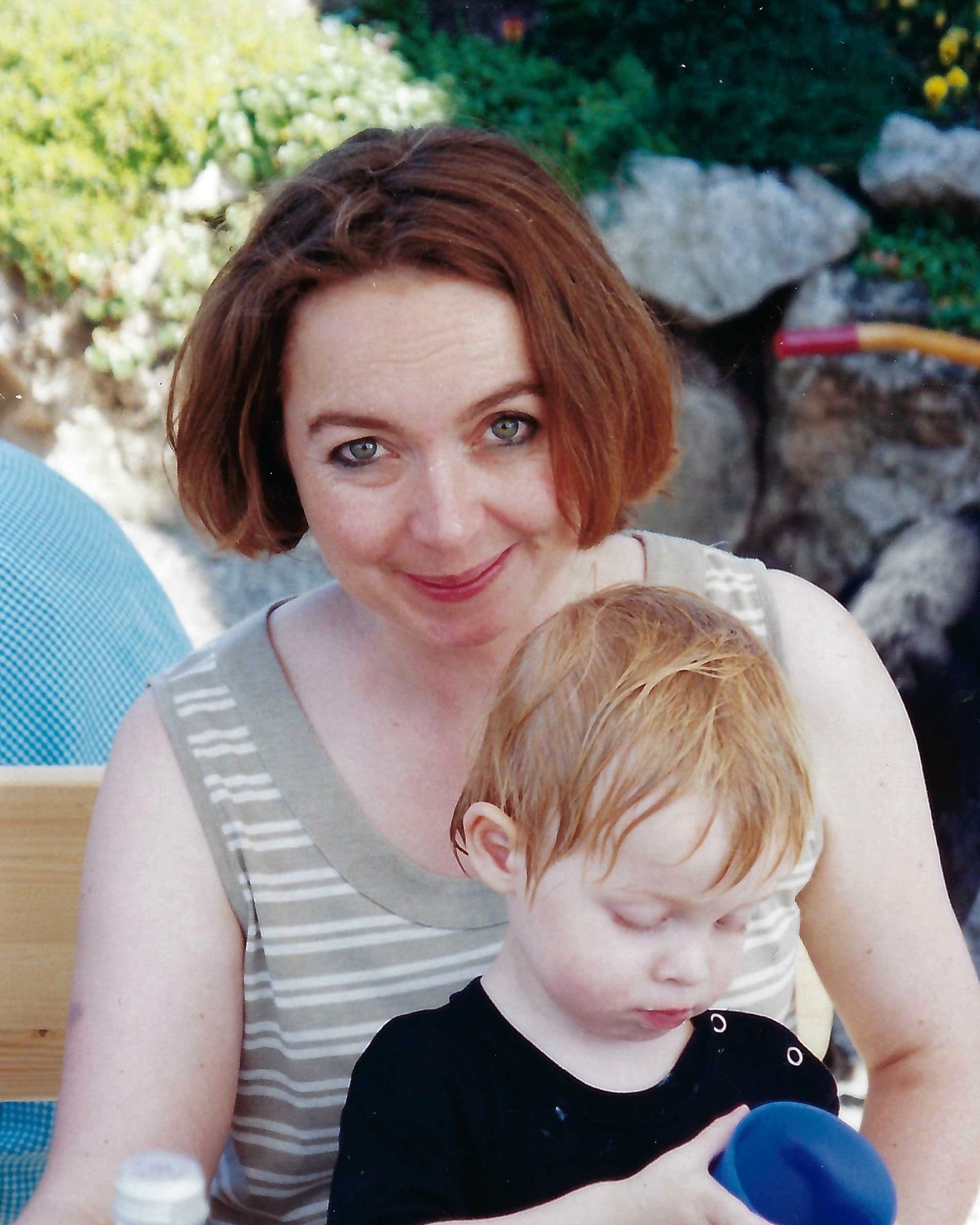 Mutter hält ihr älteres Kind liebevoll im Arm im Garten